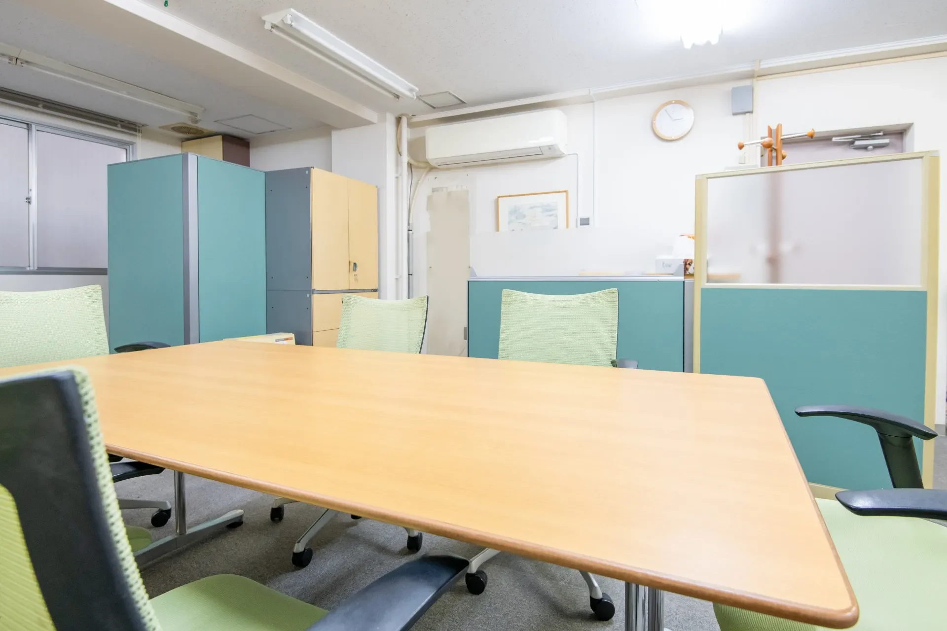 窓から光が入る会議室のテーブルと複数の椅子